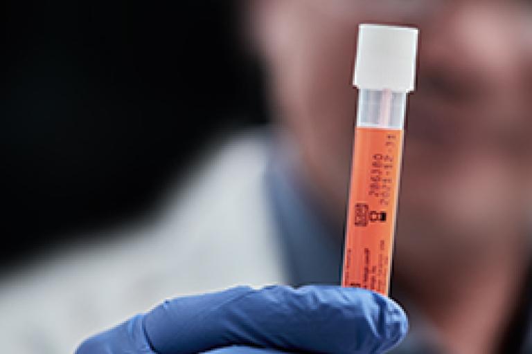 Main gantée tenant un flacon