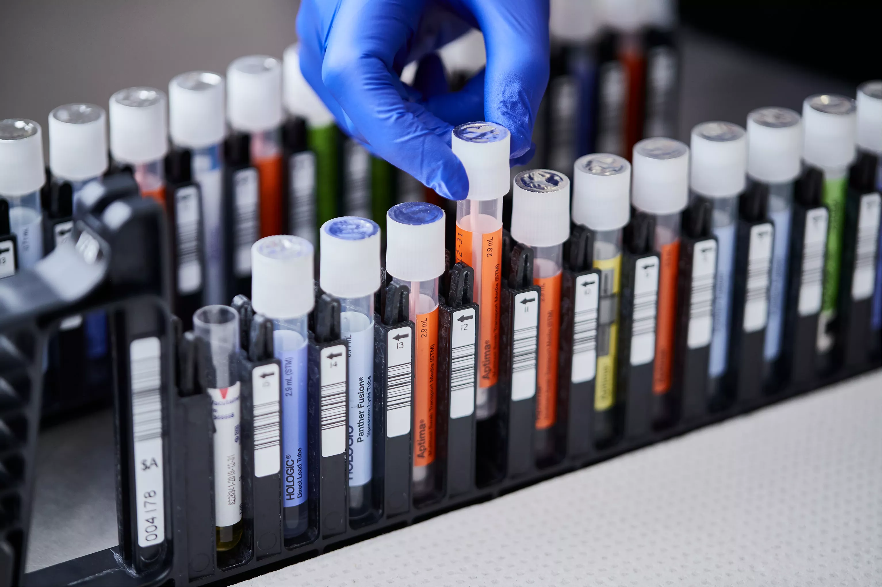 Main gantée retirant un flacon du plateau