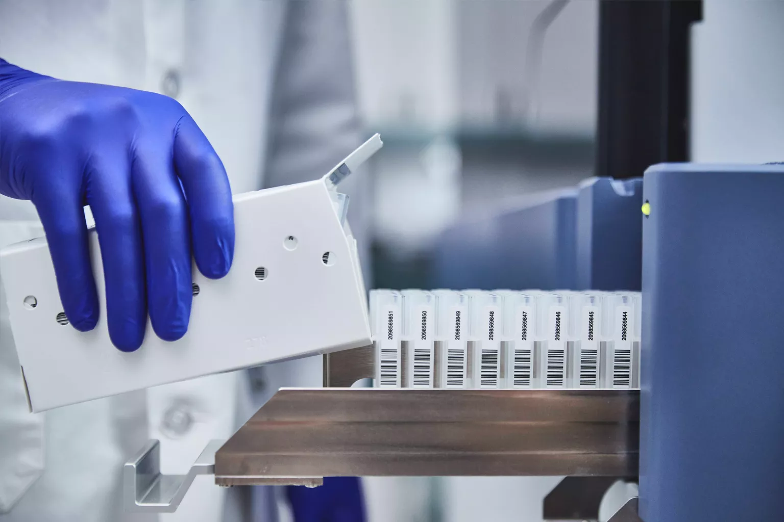 Technicien de laboratoire chargeant un plateau de tubes dans un laboratoire.