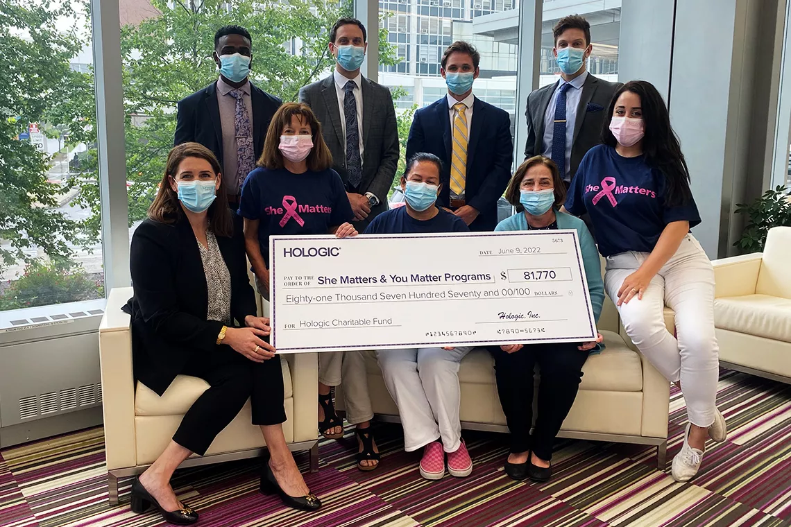 Photo d’un groupe de personnes portant un masque et tenant un grand chèque promotionnel en soutien aux programmes She Matters et You Matter