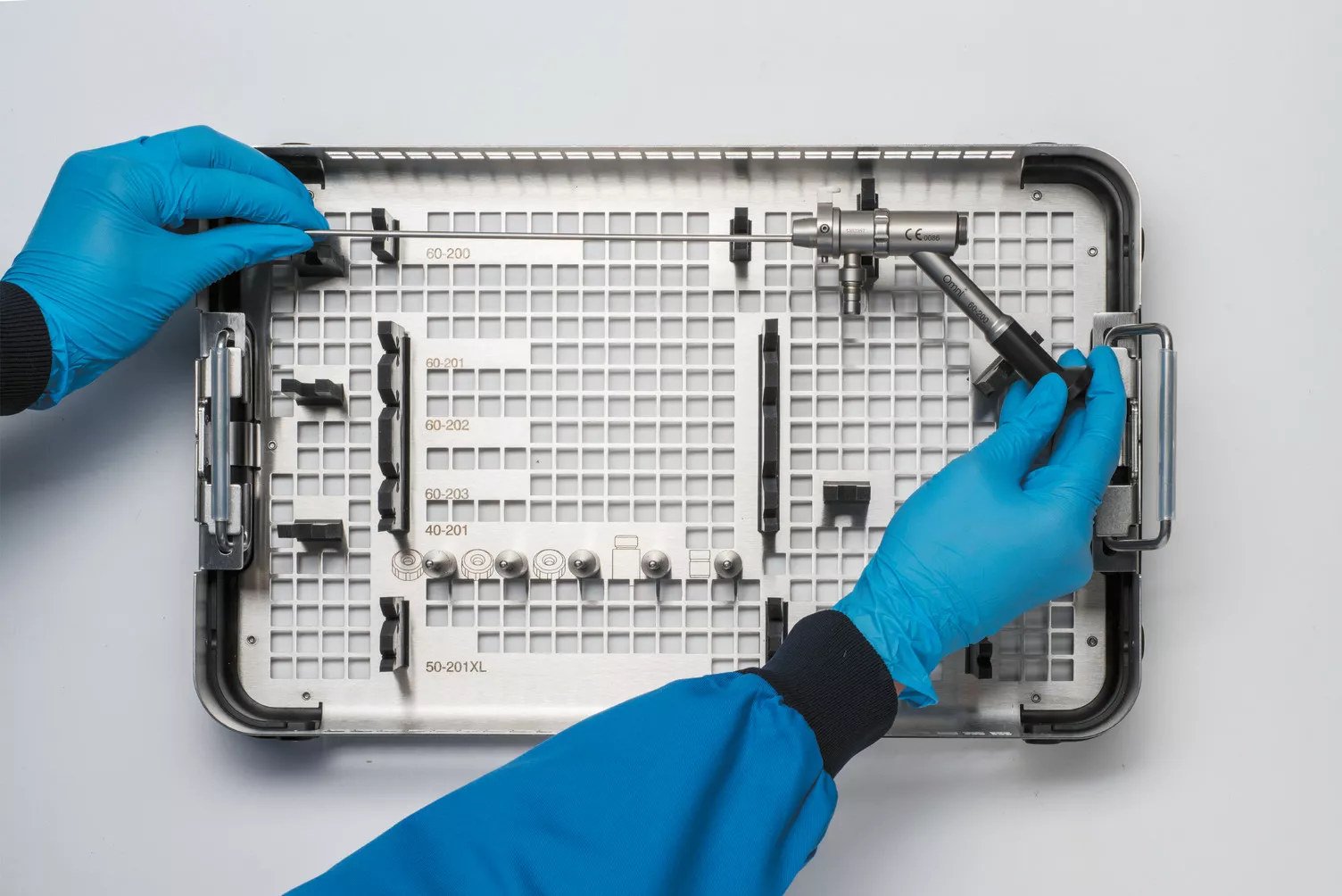 Des mains gantées travaillent sur un plateau médical posé sur une table.