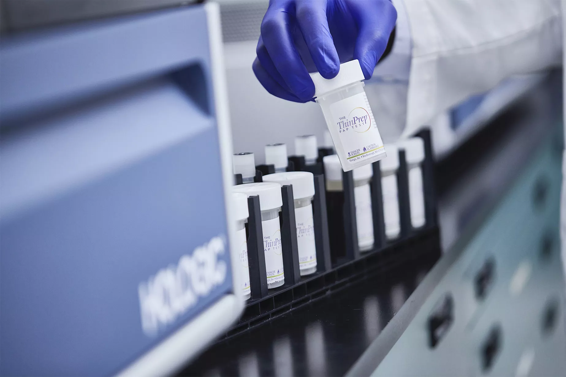 Main gantée tenant un flacon